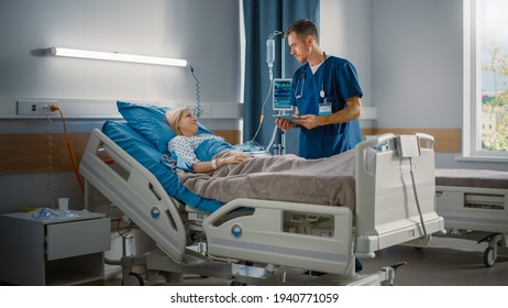 Hospital Ward: Friendly Male Nurse Talks To Beautiful Female Patient Resting In Bed. Male Nurse Or Physician Uses Tablet Computer, Does Checkup, Woman Recovering After Successful Surgery