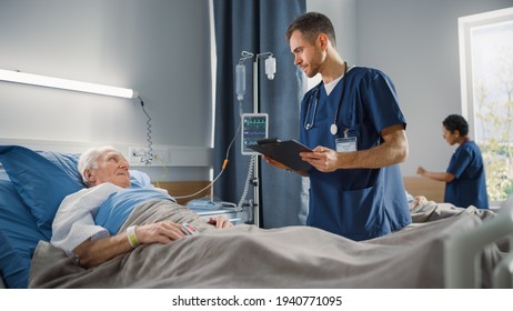 Hospital Ward: Friendly Male Nurse Talks With Elderly Patient Resting In Bed. Doctor Uses Tablet Computer, Does Checkup. Old Man Fully Recovering After Successful Surgery. Modern Bright Clinic