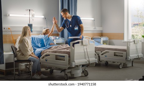 Hospital Ward: Handsome Young Boy Resting in Bed with Caring Mother Visits to Support Him, Friendly Doctor, Surgeon, Nurse Talks, Does High-Five with a Happy Smiling Patient Recovering after Sickness