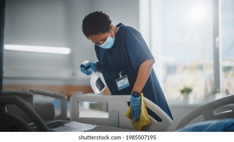 Hospital Ward: Professional Black Nurse Wearing Face Mask, Wiping The Bed, Cleaning Room After Covid-19 Patients Recover. Disinfection, Sterilizing, Sanitizing Clinic After Coronavirus Infected People