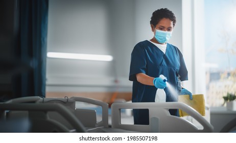 Hospital Ward: Professional Black Nurse Wearing Face Mask, Wiping the Bed, Cleaning Room After Covid-19 Patients Recover. Disinfection, Sterilizing, Sanitizing Clinic after Coronavirus Infected People - Powered by Shutterstock