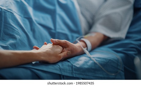 Hospital Ward: Senior Woman Resting In A Bed With Finger Heart Rate Monitor, Caring Family Member Holds Her Fragile Hand, Support And Comforting. Focus On The Hands.