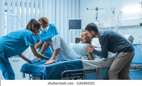 In the Hospital, Woman in Labor Gives Birth, Obstetricians and Doctors Assist, Her Husband Supports Her by Holding Hand. Modern Maternity/ Delivery Ward with Professional Midwives. - Powered by Shutterstock