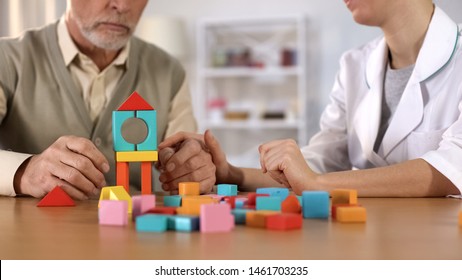 Hospital worker helping dementia patient combine color blocks, brain exercise