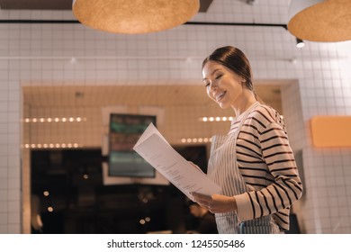 Hospitality Manager. Cheerful Professional Hospitality Manager Studying The Menu Of New Restaurant