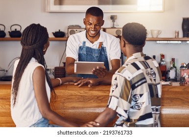 Hospitality, Service And Technology With Restaurant Worker Taking Orders On A Digital Tablet, Smiling And Talking. Young Employee Manage Customer Payment On An Online App, Paying Using The Internet