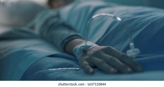 Hospitalized Patient Lying In Bed With IV Drip, Hand Close Up, Healthcare Concept