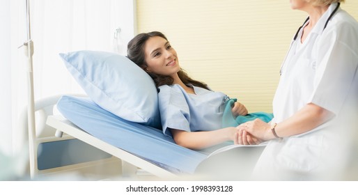 Hospitalized woman lying on the bed while a doctor examining woman patient in hosipal room.