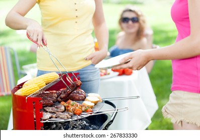 Host serving woman frazzled sausage on grill party