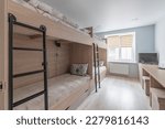 Hostel dormitory beds arranged in dorm room with white plain bunk bed in dormitory.Hostel dormitory have many beds arranged in one room. Clean hostel small room with wooden bunk beds. small hotel.