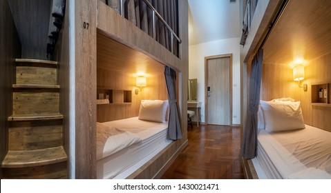 Hostel dormitory beds arranged in dorm room with white plain bunk bed in dormitory.Hostel dormitory have many beds arranged in one room. Clean hostel small room with wooden bunk beds. small hotel 