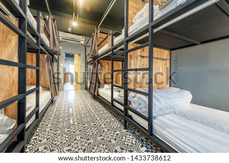 Hostel dormitory beds arranged in dorm room with white plain bunk bed in dormitory.Hotel dormitory have many beds arranged in one room. Clean hostel small room with wooden bunk beds. 