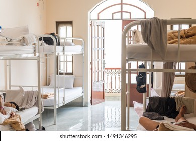 Hostel dormitory with bunk beds and sleeping travelers. Real hostel's interior with some mess.