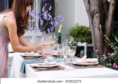 Hostess Bringing Water Jug To The Table Set For A Garden Party