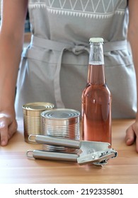 Hostess In A Gray Kitchen Apron Demonstrates A Bottle And Can Opener.