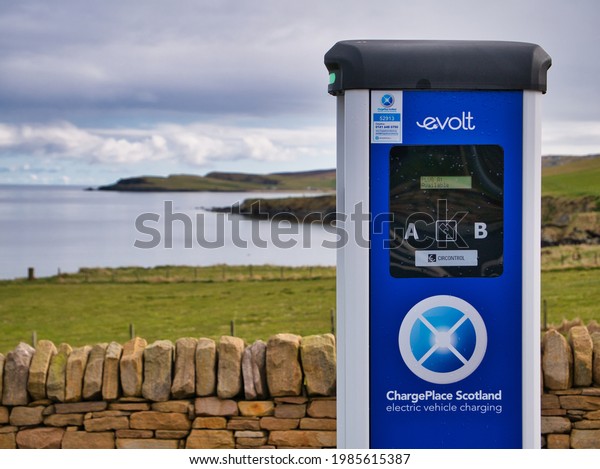 Hoswick, UK - May 1 2021: A two\
socket,  blue, evolt ChargePlace Scotland in a remote, coastal\
setting at the Visitor Centre car park in Hoswick, Shetland,\
UK.