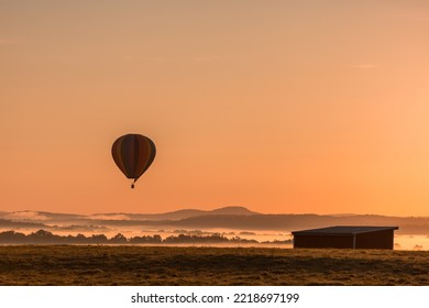 Hot Air Balloon Is Basked In A Golden Glow As It Slowly Ascends Over A Fog-filled Valley In Orange County, NY, On An Early Fall Morning