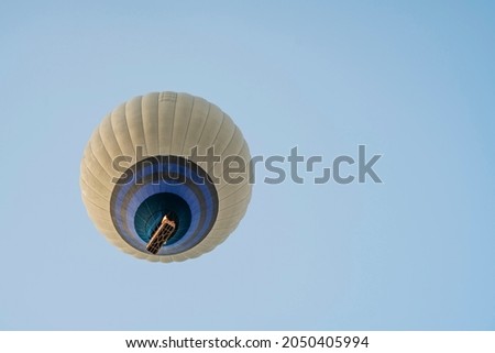 Hot air balloon flight in the blue sky with an open parachute made of gray fabric and a basket. Bottom view. Fun and happiness. Relaxing flight. copy space