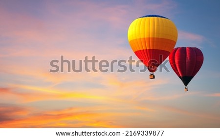 Hot air balloon floating in vivid sky with cloud painted by the sun before sunset in winter. Colorful sky on evening time. Bright blue, orange and yellow colors sunset .