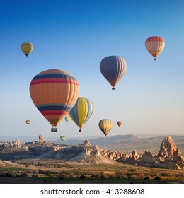 Hot air balloon flying above rocky landscape in Cappadocia, Turkey
