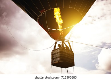 Hot air balloon flying in a cloudy sky at sunrise - Image of balloon silhouette flight over the sky 