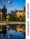 Hot air balloon flying over the Castle of Vajdahunyad in the City Park of Budapest, with water reflection