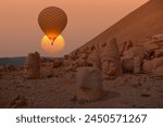 Hot air balloon flying over Statues God on top of the Nemrut Mountain at sunset - Adiyaman, Turkey