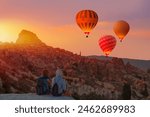 Hot air balloon flying over spectacular Cappadocia - Girls watching hot air balloon at the hill of Cappadocia