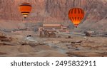 Hot air balloon flying over Hatshepsut Temple at sunrise in Valley of the Kings and red cliffs western bank of Nile river - Luxor- Egypt