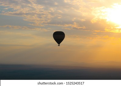 Hot Air Balloon Flying Over The Wide Open Plains Of The Masai Mara National Reserve In Kenya, Africa At Sunrise.