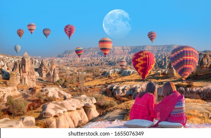 Hot air balloon flying over spectacular Cappadocia - Japanese girls watching hot air balloon at the hill of Cappadocia "Elements of this image furnished by NASA - Powered by Shutterstock