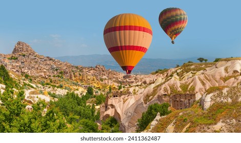 Hot air balloon flying over spectacular Cappadocia, Uchisar castle in the background - Goreme, Turkey - Powered by Shutterstock