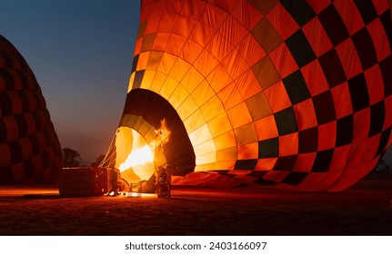 Hot air balloon is inflating before liftoff - Hatshepsut Temple at sunrise in Valley of the Kings and red cliffs western bank of Nile river- Luxor- Egypt - Powered by Shutterstock