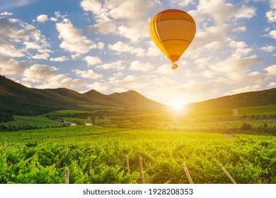 Hot air balloon over the mountains and vineyards.