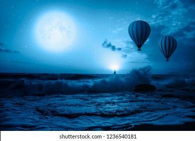 Hot air balloon over the stormy sea against super blue full moon and lighthouse at night