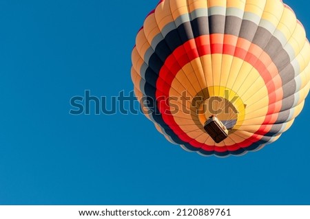 hot air balloon takes off at sunrise, blue sky behind, bottom angle view