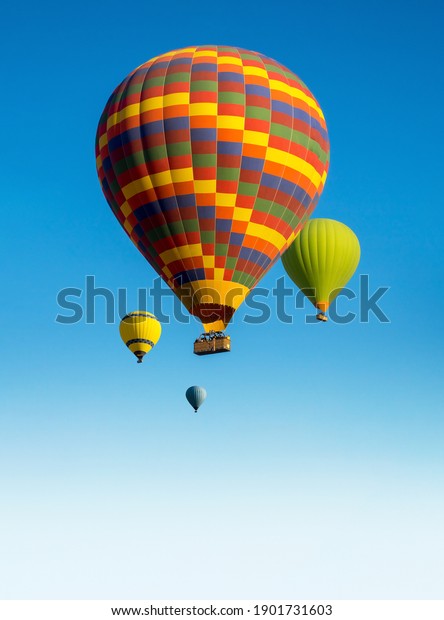 Hot air balloons against a background of blue\
sky with a copy space. Composition with colorful gas balloons as a\
landscape for promotion of travel agency or your stories of\
ballooning to Cappadocia.