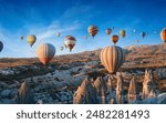 Hot air balloons floating over unique rock formations of Cappadocia, Turkey at sunrise. Vibrant balloons contrast with the rocky landscape and blue sky. Welcome to Cappadocia concept image