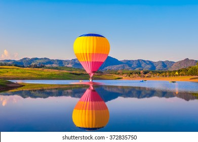 Hot air balloons floating over lake