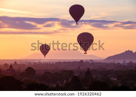 Hot air balloons fly over the ancient pagodas of old Bagan in Myanmar at sunrise. Bagan, Myanmar.