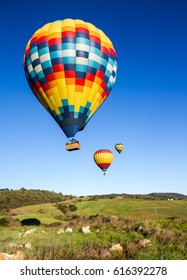 Hot air balloons over Napa Valley vineyards at sunrise with blue sky
