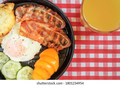 Hot American Breakfast With Fried Egg, Delicious Bacon And Sliced Vegetables On Black Plate. Flay Lay. Copy Space. 