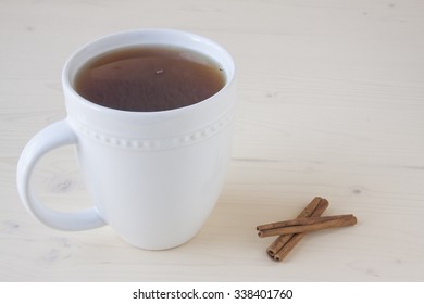 Hot Apple Cider And Cinnamon Sticks On A White Wooden Background