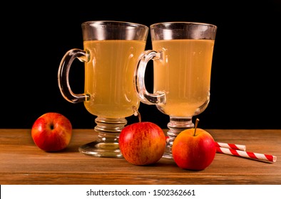 Hot Apple Cider In The Glass Mugs With Straws And Apple Fruits Isolated On A Black Background.