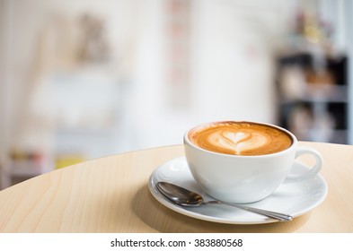 Hot art Latte Coffee in a cup on wooden table and Coffee shop blur background with bokeh image