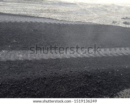 Hot asphalt and tire marks on it close-up.