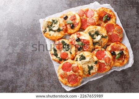 Hot assorted mini pizza or Pizzette with various toppings close-up on parchment on the table. horizontal top view from above
