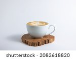 Hot cafe Latte espresso coffee in white ceramic cup on wood saucer with rosetta latte art isolated in white background.
