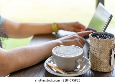 Hot Cappuccino Coffee For Quarantined Woman Wear Face Mask And Work From Home By Using Tablet And Stress Relief With Hot Coffee. Concepts Of Covid-19 (Coronavirus Disease). Selective Focus On Coffee.