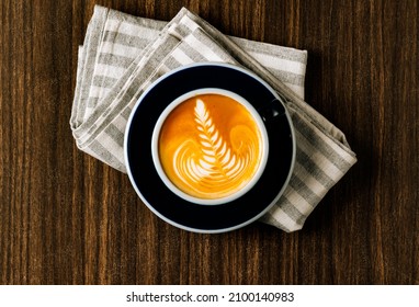 Hot Caramel Latte Macchiato Coffee With Coffee Beans In A Black Mug Top View In Dark Wooden Table Background.